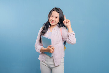 Fototapeta premium A woman is holding a blue book and pointing to something important. She is smiling and she is happy