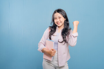 A woman is holding a pink book and is smiling