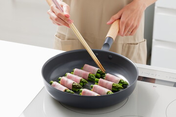 フライパンでアスパラベーコンを焼く料理のシーン　Asparagus Bacon Being Cooked in a Frying Pan