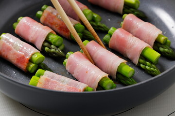 フライパンでアスパラベーコンを焼く料理のシーン　Asparagus Bacon Being Cooked in a Frying Pan