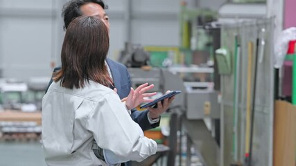 A male business person and a female worker inspecting a factory