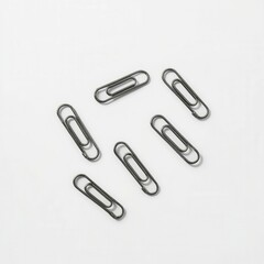 A row of black paper clips are lined up on a white background. The clips are all the same size and shape, and they are all facing the same direction. Concept of order and uniformity