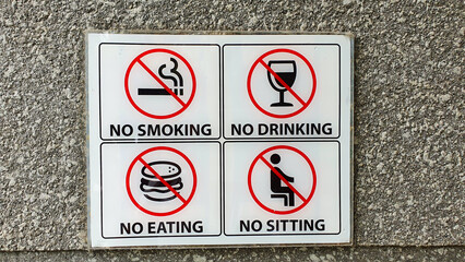 Many prohibition signs on a wall. No smoking, no drinking, no eating, no sitting.