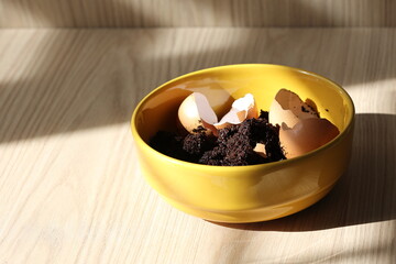 Tired coffee grounds and eggshells in compost bowl