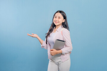 A woman is holding a tablet and pointing to it. She is smiling and she is happy
