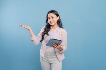 A woman is holding a tablet and pointing to it. She is smiling and she is happy