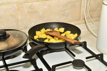 Kitchen. There is a frying pan with food on the surface of the gas stove.
