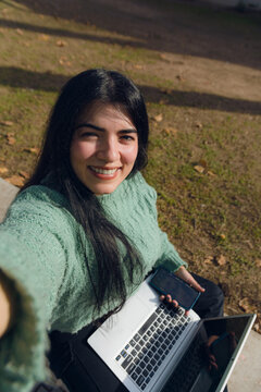 Vertical image of a selfie photo of an entrepreneurial woman in the park, calm and with her laptop