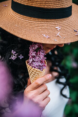 spring lilac flowers in an ice cream cone held by a young woman with black hair