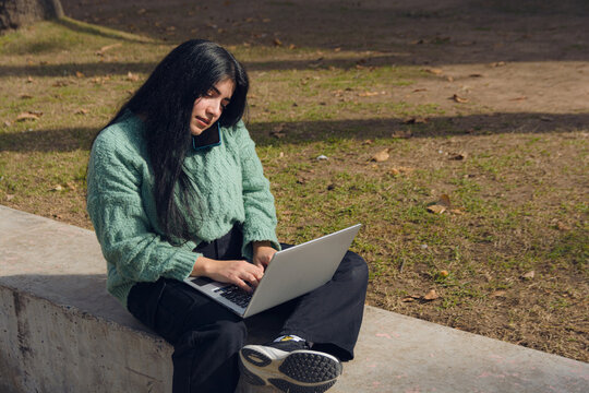 Young entrepreneur outdoors talking on the phone and typing on the laptop at the same time