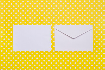Two white envelopes on a yellow with white polka dots background with copy space