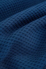 Macro close-up of dark blue fleece fabric with a waffle-knit structure, showing detailed grid-like texture and soft folds across the surface.
