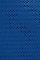 Macro top-down view of a blue synthetic surface with a geometric pattern of circular perforations, forming a gradient density grid across the frame.