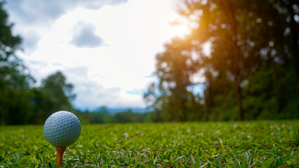 Golf ball on tee in beautiful golf course at sunset.