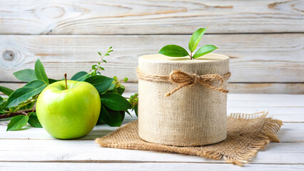 Green apple and gift box with leaves on a wooden table