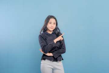 A woman is pointing at something with her finger. She is wearing a black shirt and white pants. She is smile and happy