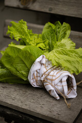 Curly and romaine lettuce bouquet resting on a wooden bench. Fresh, raw and rustic feel.