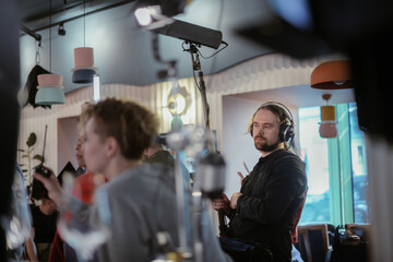 Sound engineer with a microphone on the set. A professional sound engineer at work on the filming of a movie, commercial or TV series. Filming process indoors, studio