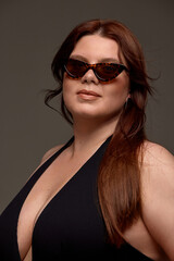 A plus-size woman confidently models chic swimwear and sunglasses, promoting empowerment and body positivity. Concept of embracing diversity and self-love in fashion.