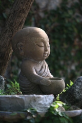 Serene Contemplation: An adorable statue of a small monk meditates in tranquil garden, conveying inner peace. 