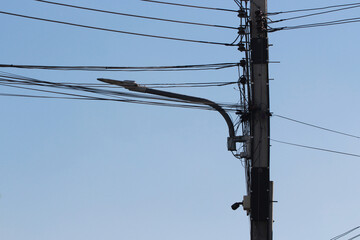 Streetlight and Wires: A close-up view of a streetlight mounted on a utility pole, surrounded by a complex network of electrical wires against a clear blue sky.