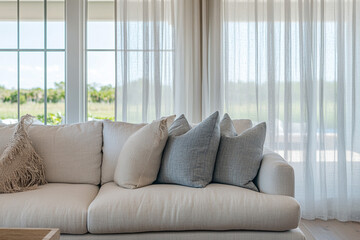 Fototapeta premium Contemporary coastal living room with linen sofa and sheer curtains