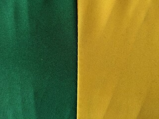 A minimalist background of green and yellow fabric stitched together, creating a simple and...