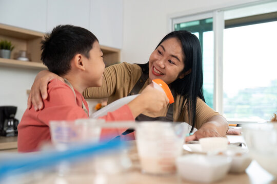 Cleaning and Baking. Mother and son sharing a delightful moment while preparing in the kitchen.