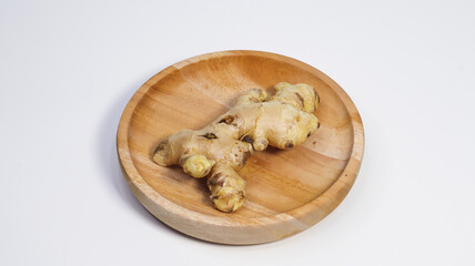 Ginger on Wooden Plate: A vibrant ginger root, nestled on a rustic wooden plate, celebrates...