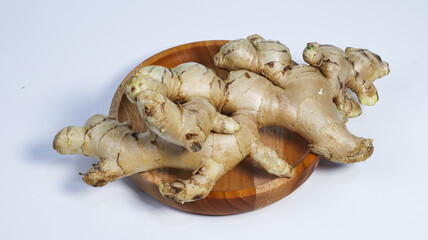 Ginger Root in Wood Plate: A close-up shot of several ginger roots arranged artfully on a round wooden plate, presented with a simple, elegant aesthetic. Capturing the natural essence.