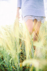 Girl in a field surrounded by golden grass, wearing a light sweater and a lace skirt, enjoying a...
