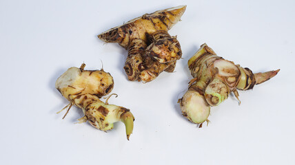 Fresh Galangal Roots: Three fresh galangal roots are elegantly arranged, displaying their textured...