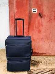Travel suitcase placed beside an old weathered door