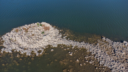 Ancient nuraghe ruins partially submerged in a Sardinian lake, exposed by low water