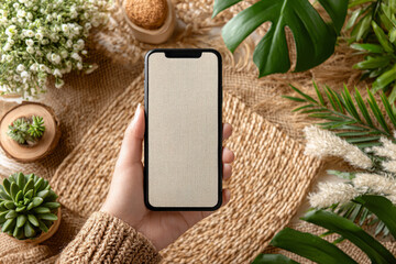 Hand holding smartphone with blank screen in natural eco setting