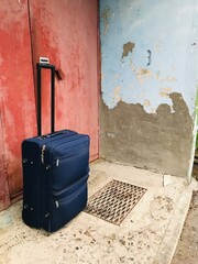 Travel suitcase resting against a weathered wall outside