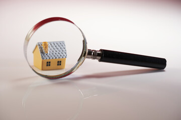 close up magnifying glass on small doll house against white background