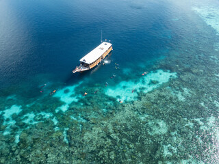 Snorkelers explore the edge of a coral reef within Wakatobi National Park, off the coast of Sulawesi. This area is a popular destination for divers and snorkelers due to its high marine biodiversity.