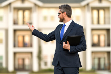 Mortgage insurer presenting house. American sales manager. Real estate agent at house for sale. Realtor in suit. Rent or buy new home. Home insure. Property insurance promotion. Successful broker