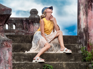 A woman sits on ancient ruins in Nha Trang, Vietnam - a moment of silence amidst the historical heritage and nature of Southeast Asia. Tourism concept