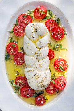 Braided Mozzarella Cheese with addition fresh tomatoes and herbs sprinkled wit olive oil, top view