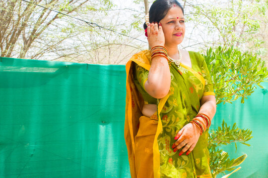 Portrait of Beautiful Indian married lady in traditional sidha palla or front pallu yellow green saree, bangles, bindi, sindoor, mehndi on hand, juda hairstyle. Ready for any festival, wedding