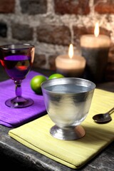 A stylish arrangement featuring drinks in metal and glass cups, candles, and vibrant colors on a rustic table.
