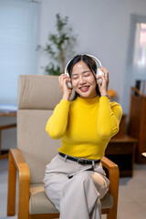 A woman in a yellow shirt is sitting in a chair and listening to music