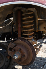 An old truck chassis with rusty coil spring and wheel hub