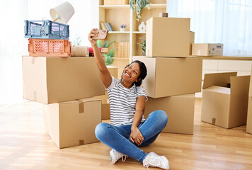 Portrait of a young woman girl unpacking boxes after moving in and relocation and making a selfie...