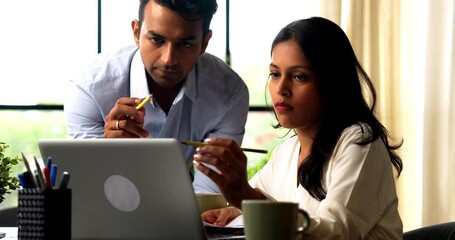 Indian business people using laptop and documents, Asian corporate man and woman in formal attire discussing reports, working together with laptop at modern indoor office desk, teamwork concept - Powered by Adobe
