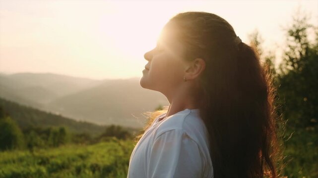 Cute child breathing fresh air. Kid faith, praise and happiness and freedom. Preteen resting in mountains. Little girl put face to the sun, closed her eyes and feeds energy of nature, dreams concept