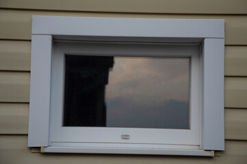 A sleek, modern window showcases a twilight sky reflection on the exterior of a residential...