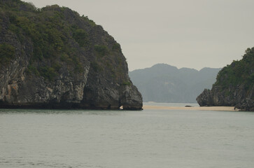 Limestone cliffs and sandy beach. Lan Ha Bay. Cat Ba Archipelago. Vietnam.